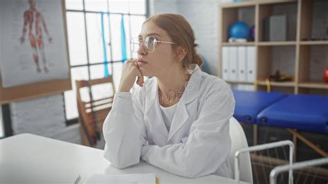 Pensive Young Woman in White Coat Sitting in a Physiotherapy .